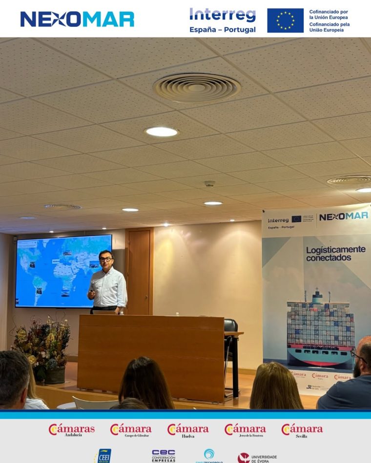 Speaker at a wooden podium presenting to an audience in a conference room; a world map on a screen behind him and a 'Logísticamente conectados' banner to the right. | PymesAutonomos.com