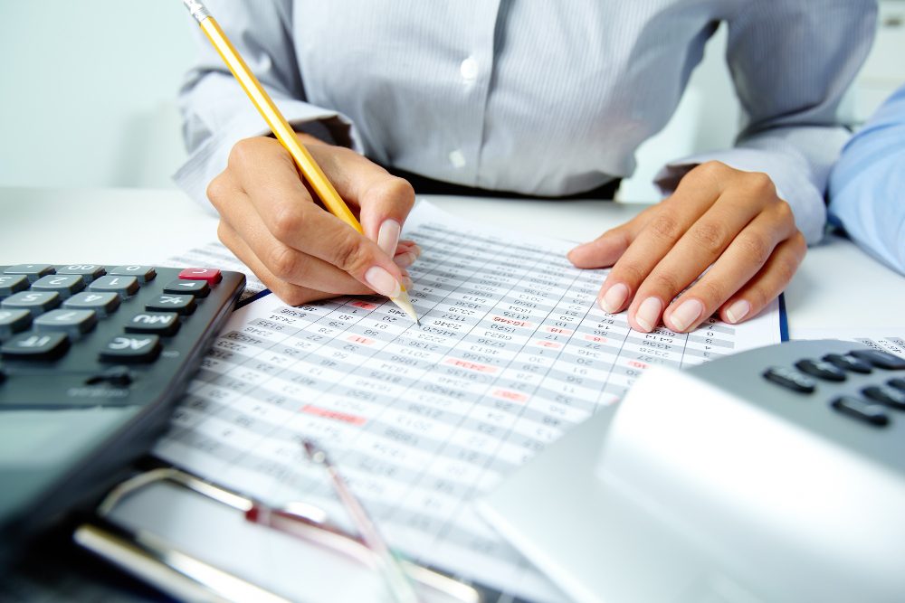 778603 - Lex Beckham | PymesAutonomos.com Person calculating finances: filling out a numeric spreadsheet with a pencil, calculator, and glasses on a desk | PymesAutonomos.com